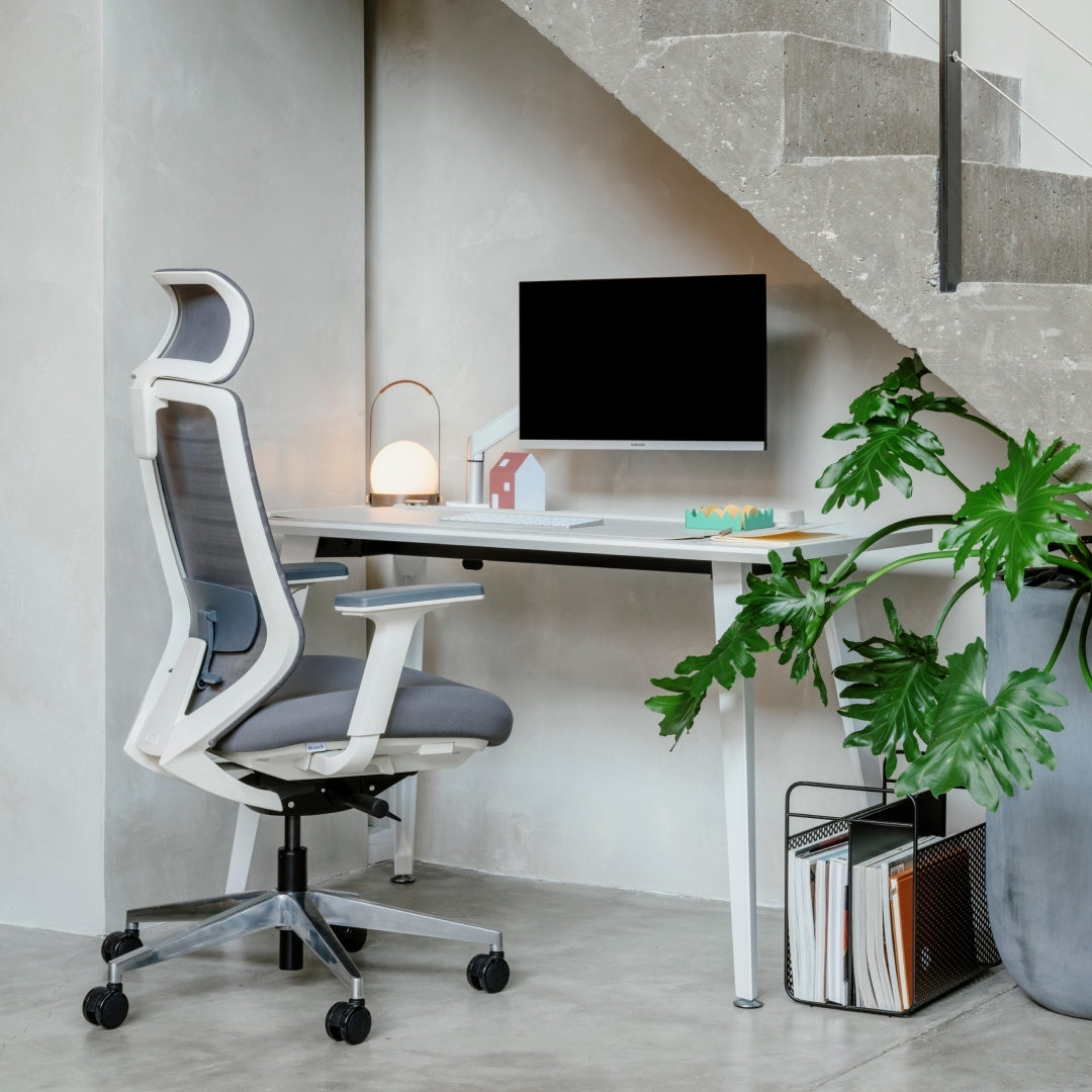 Modern gray ergonomic office chair by Pelicanwork at sleek desk with monitor and plant