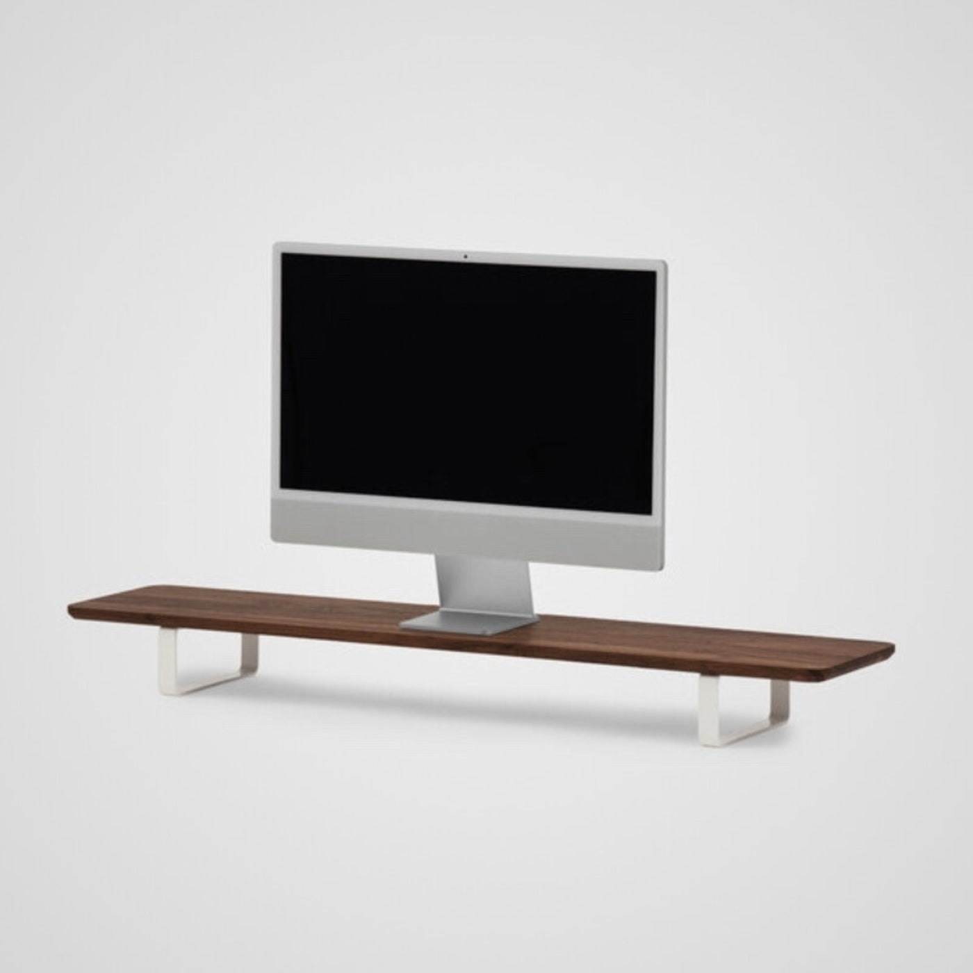 walnut monitor stand with white metal legs, holding computer monitor, minimalist desk accessory