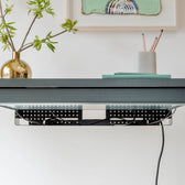 Black cable organizer mounted under a modern office desk, neatly managing cords