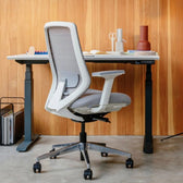 Model 11 white ergonomic office chair at adjustable desk, modern workspace setup