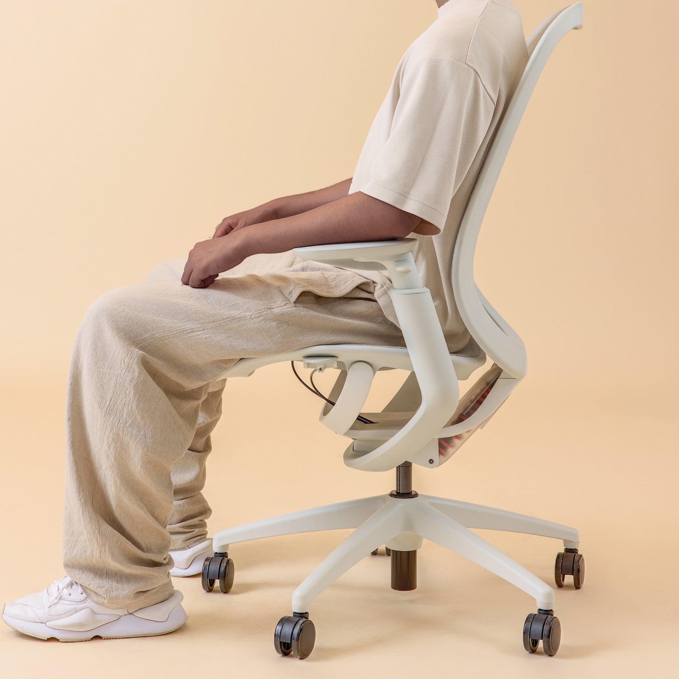 Side view of person sitting on a white ergonomic office chair with adjustable armrests